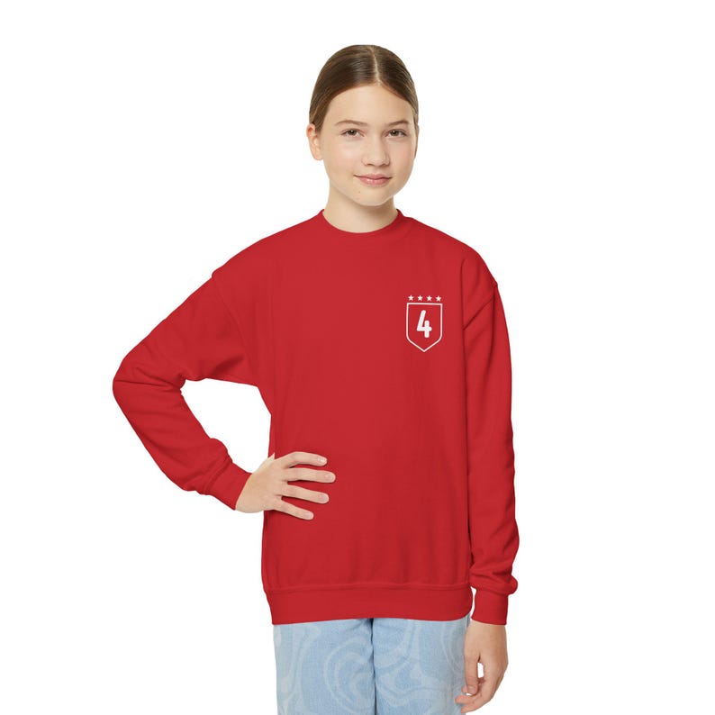 K&ouml;nnte beinhalten: Roter Pullover mit einem wei&szlig;en gestickten Schild mit der Nummer 4 und f&uuml;nf Sternen dar&uuml;ber.