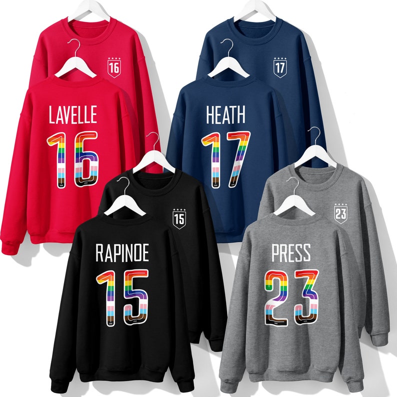 May include: Five crew neck sweatshirts with rainbow numbers and names on the front. The names are Lavelle, Heath, Rapinoe, Press, and the numbers are 16, 17, 15, and 23.