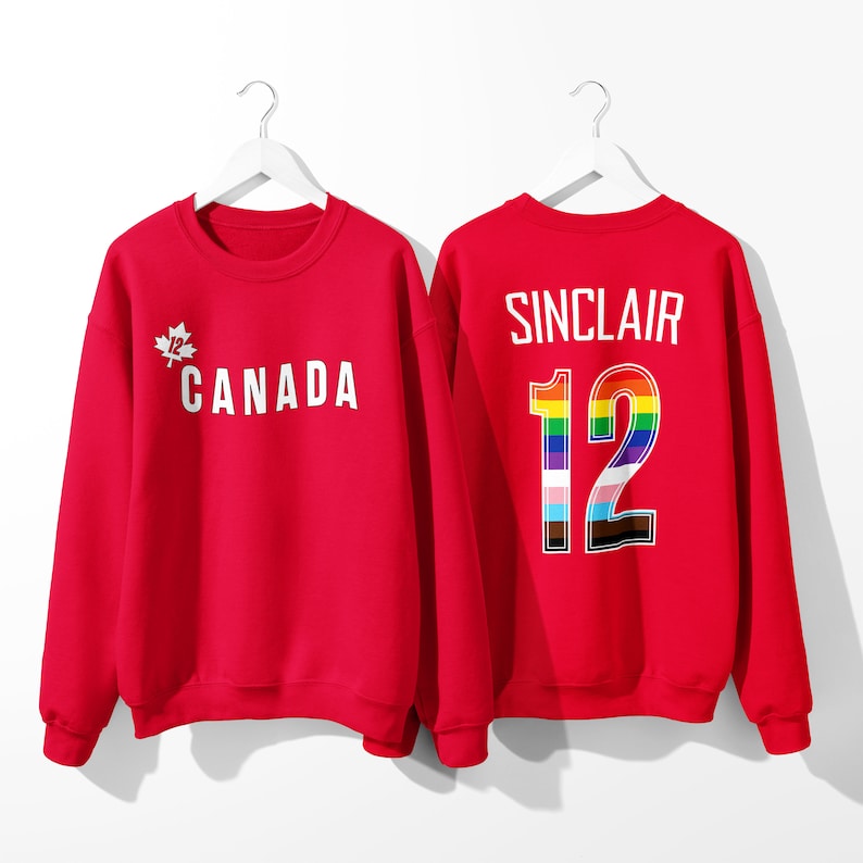 May include: Red sweatshirt with a white maple leaf and the word "CANADA" on the front and the name "SINCLAIR" and the number "12" with a rainbow design on the back.