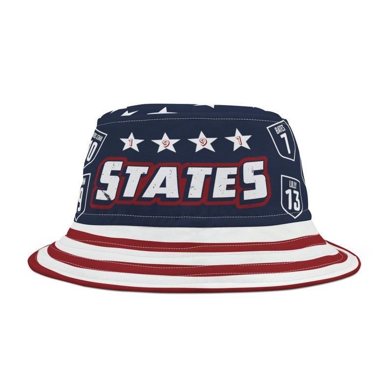 May include: A blue and red bucket hat with a white star pattern and the word "STATES" in a red, white, and blue design. The hat also has a red, white, and blue stripe pattern around the brim.