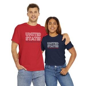 K&ouml;nnte beinhalten: Zwei Personen tragen rote und marineblaue T-Shirts mit dem Aufdruck "United States Women's Soccer".