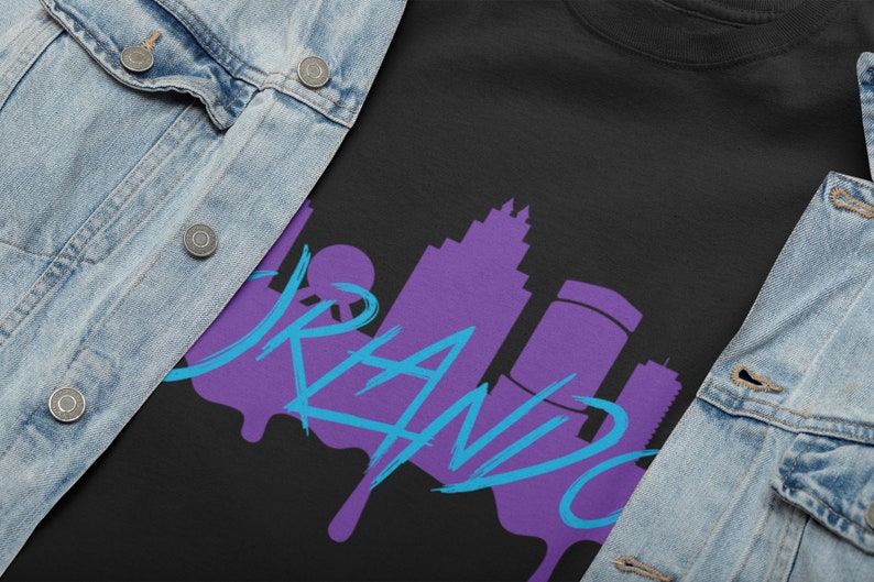 May include: A black t-shirt with a purple and blue graphic design of the Orlando skyline and the word "Orlando" in a dripping paint style.