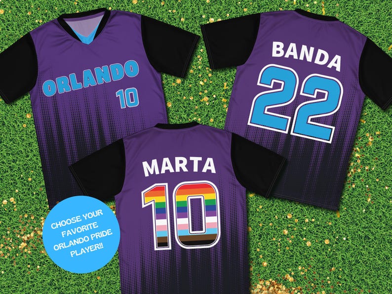 Op de afbeelding: Drie paarse voetbalshirts met zwarte mouwen. De shirts hebben verschillende namen en nummers op de rug. Het eerste shirt heeft "ORLANDO 10" op de rug. Het tweede shirt heeft "BANDA 22" op de rug. Het derde shirt heeft "MARTHA 10" op de rug met een regenboognummer.