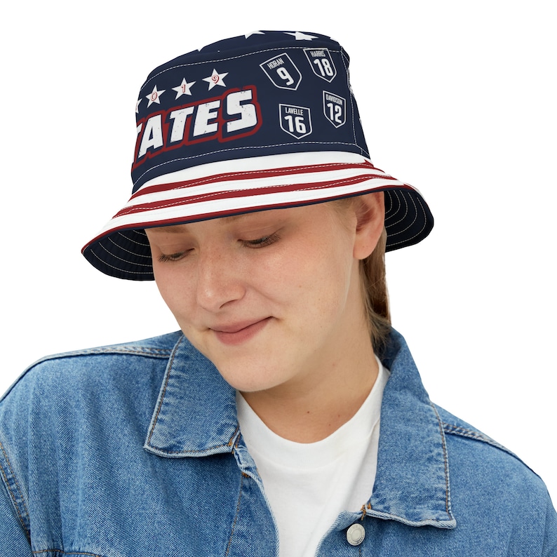 May include: A blue and red bucket hat with a white star pattern and the word "STATES" in white letters. The hat also has red and white stripes around the brim and features numbers and names on the front.