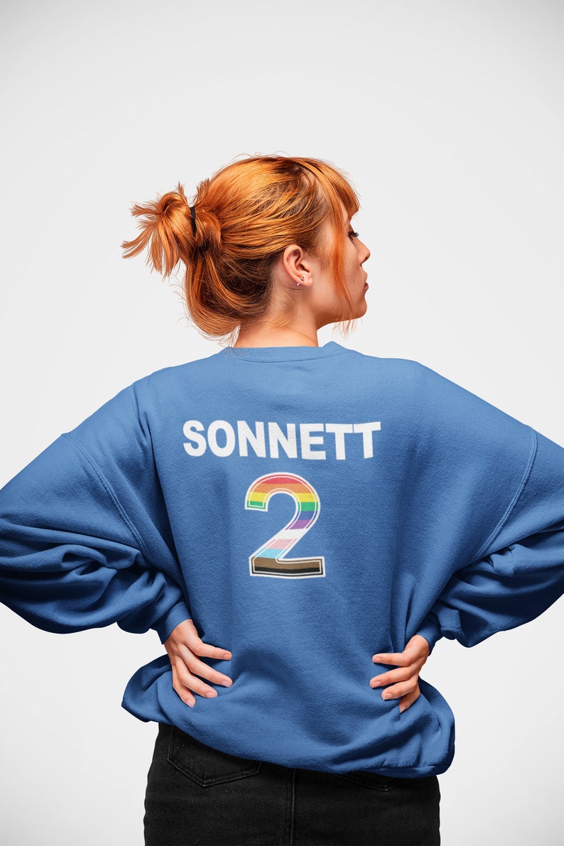 May include: A royal blue sweatshirt with the word "SONNETT" and the number "2" printed on the back. The number is outlined in black and filled with a rainbow color scheme.