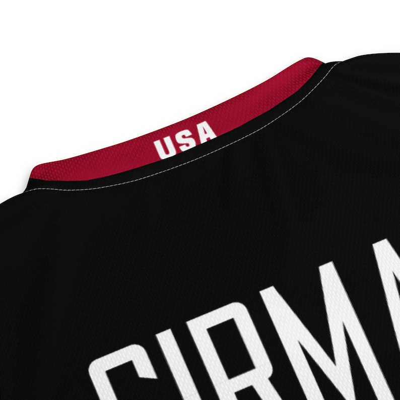 May include: Black basketball jersey with a red collar and white text that says "USA" on the collar and "CIRMA" on the back.