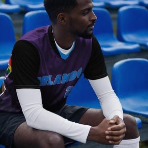 Op de afbeelding: Een basketbaltrui met een paars en zwart ontwerp. De trui heeft het woord "ORLANDO" in blauwe en witte letters op de voorkant. De trui heeft ook het nummer "2" in wit op de voorkant.
