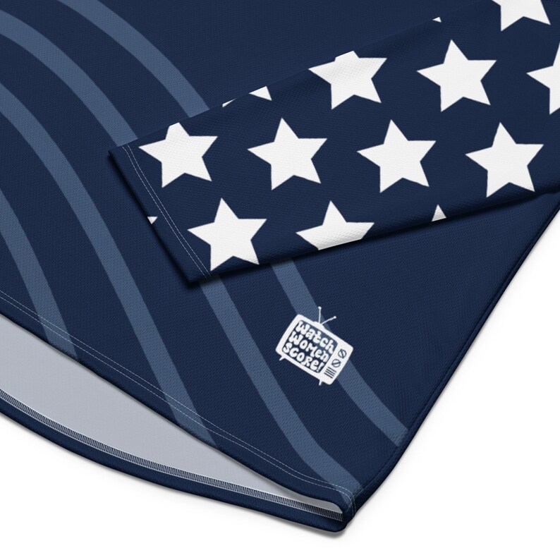 May include: Navy blue long-sleeved shirt with white stars on the sleeves and a white graphic of a television with the text "Watch Women Score!" on the front.