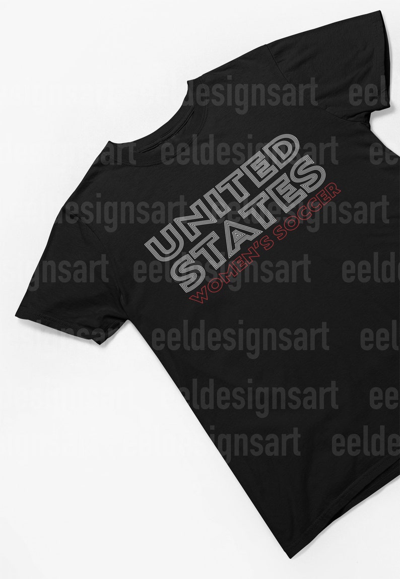 K&ouml;nnte beinhalten: Schwarzes T-Shirt mit einem wei&szlig;en Grafikdesign, auf dem in einer stilisierten Schrift "UNITED STATES WOMEN'S SOCCER" steht.