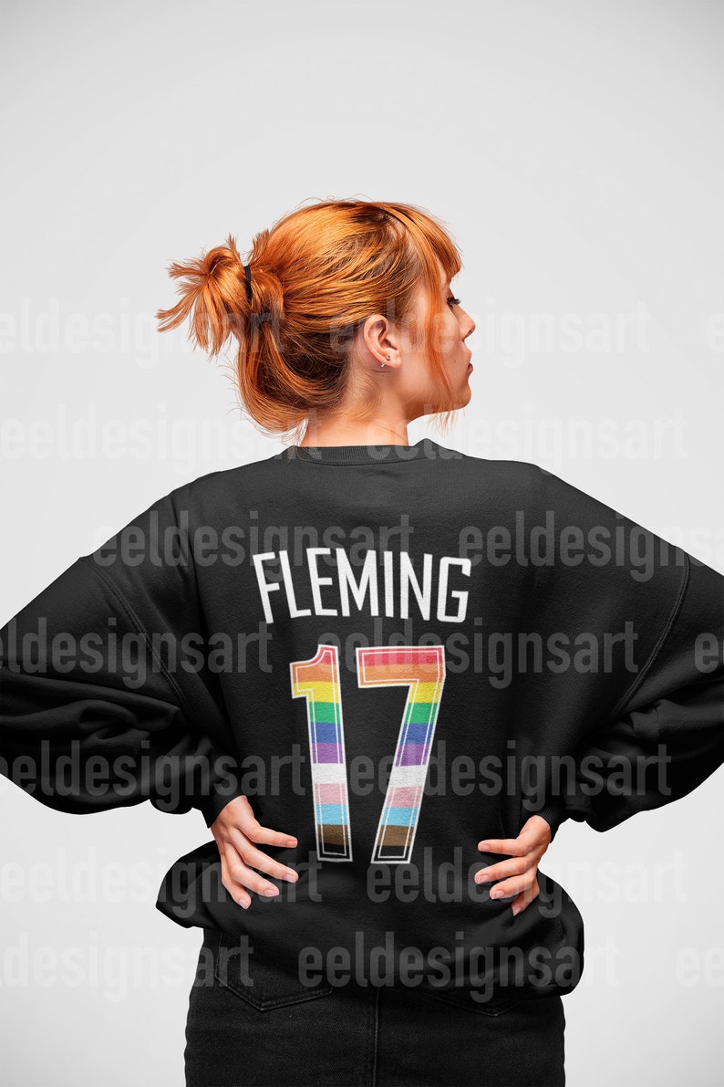 May include: Black sweatshirt with a rainbow-colored number 17 and the name "FLEMING" printed on the back.
