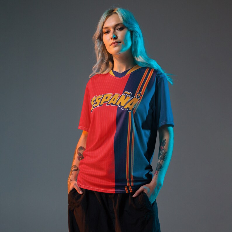 May include: A red and blue jersey with the word "ESPA&Ntilde;A" in yellow letters. The jersey has a white star on the right side of the chest.