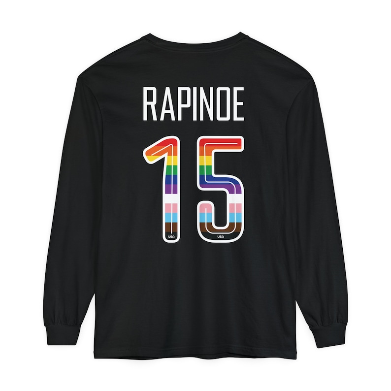 Op de afbeelding: Zwart longsleeve shirt met de naam "RAPINOE" en het nummer "15" in regenboogkleuren op de achterkant.