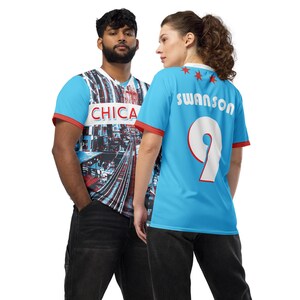 Op de afbeelding: Twee mensen dragen blauwe en rode voetbalshirts. Het shirt aan de linkerkant heeft een stadsbeeldontwerp met het woord "CHICA" erop. Het shirt aan de rechterkant is effen blauw met het woord "swanson" en het nummer "9" erop.