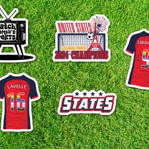 May include: Four stickers featuring a television with the text "Watch Women's Sports", a soccer jersey with the number 9 and the text "SWANSON", a soccer jersey with the number 15 and the text "LAVELLE", and a soccer goal with the text "UNITED STATES GOLD MEDAL WINNERS 2024 CHAMPIONS" and a sticker with the text "STATES" with five stars.