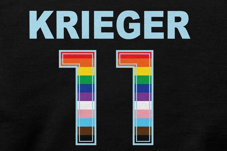 Puede incluir: Jersey negro con el nombre "KRIEGER" en letras azul claro y el n&uacute;mero "11" en un esquema de colores arco&iacute;ris con un contorno azul claro.