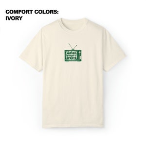 May include: A cream colored t-shirt with a green retro television graphic that says "Watch Women's Sports".