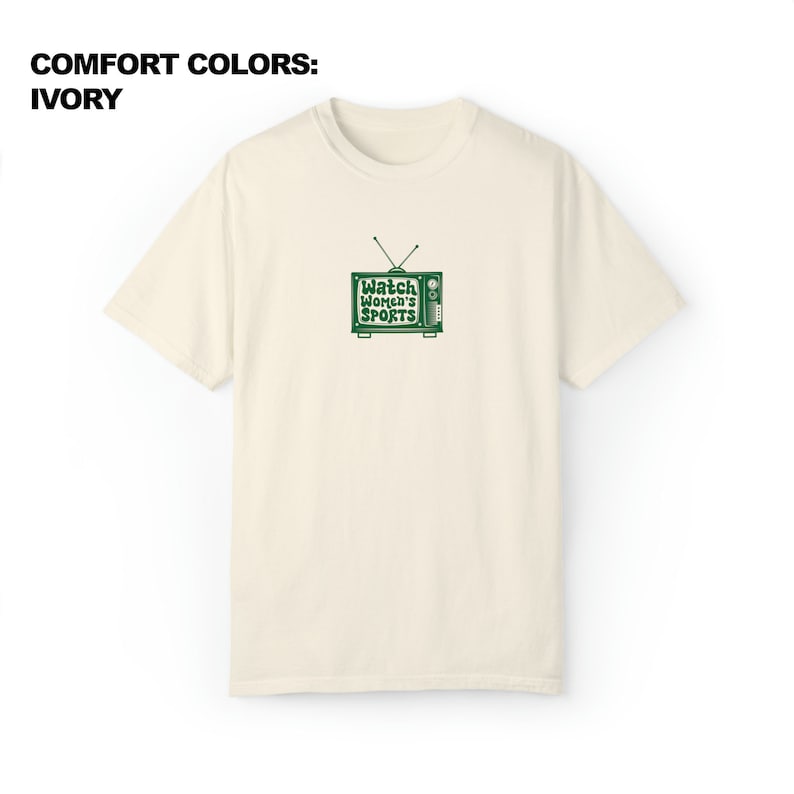 May include: A cream colored t-shirt with a green retro television graphic that says "Watch Women's Sports".