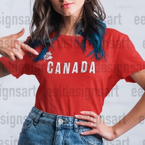 May include: A red t-shirt displaying the word "CANADA" in white capital letters. Above the word is a white maple leaf with the number "17". The person in the image is wearing blue denim jeans.