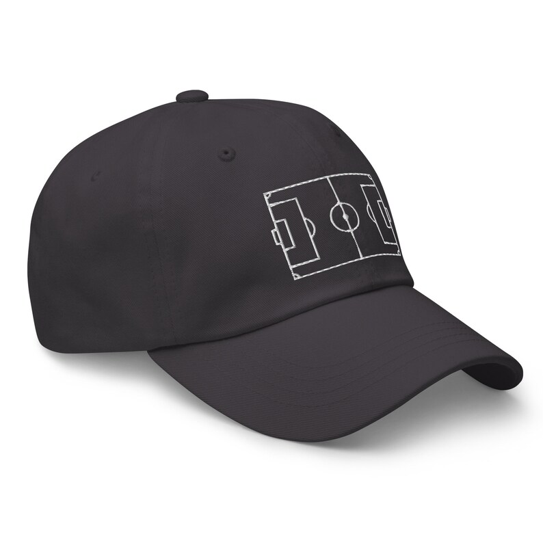 May include: A dark grey baseball cap with a white outline of a football pitch embroidered on the front.