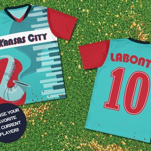 May include: Two teal blue soccer jerseys with red sleeves. The front jersey has a saxophone and piano keys design with the text "Kansas City". The back jersey has the text "Labonta 10".
