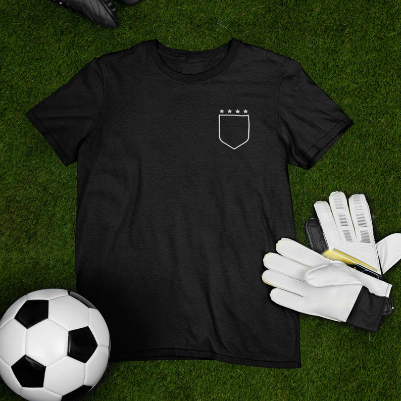 May include: Black t-shirt with a white outline of a shield and five stars on the left chest.