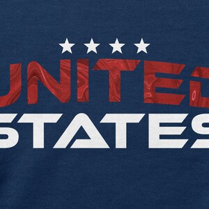 Op de afbeelding: Een marineblauw t-shirt met een rood en wit grafisch ontwerp dat "UNITED STATES" zegt met vijf witte sterren boven het woord "UNITED".