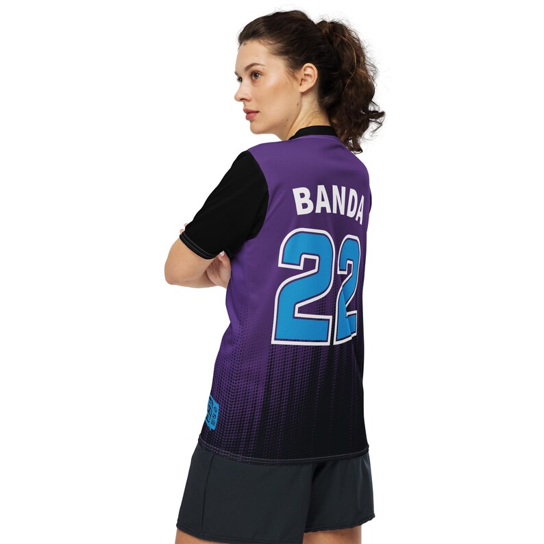 Op de afbeelding: Paars en zwart voetbaltenue met een blauw nummer 22 en het woord "Banda" op de rug.