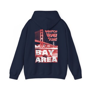 May include: Navy blue hooded sweatshirt with a red and white graphic print of the Golden Gate Bridge and the text "Watch Women Score! Bay Area".