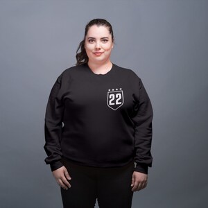 May include: A black sweatshirt with a white shield design featuring the number 22 and five stars.