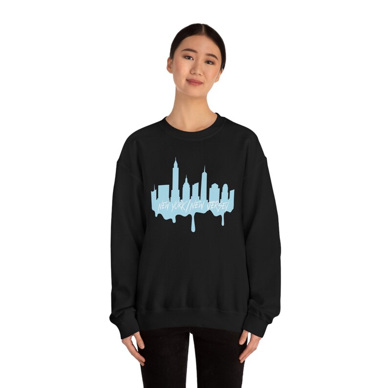 May include: Black sweatshirt with a light blue graphic of the New York City skyline with the text "NEW YORK/NEW JERSEY" underneath. The graphic is dripping down like melted ice cream.