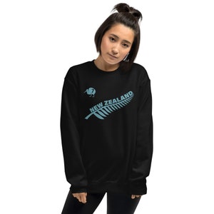 May include: Black sweatshirt featuring a blue kiwi bird and fern leaf design. The text "NEW ZEALAND" is written on the fern leaf.