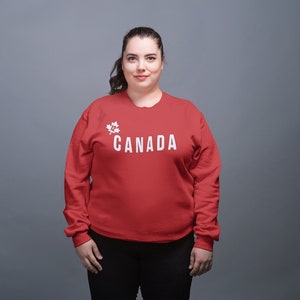 May include: A red sweatshirt with a white maple leaf and the word "CANADA" printed on the front.