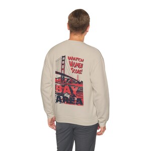 May include: A light gray sweatshirt with a graphic print of the Golden Gate Bridge and the text "Watch Women Score! Bay Area" in red and blue.
