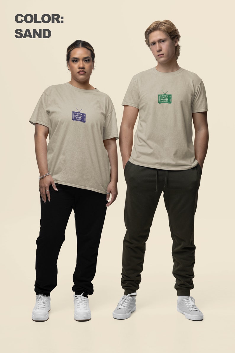 May include: Two people wearing sand colored t-shirts with a vintage television graphic. The television graphic on the left shirt is blue and the graphic on the right shirt is green. Both people are wearing black pants and white sneakers.
