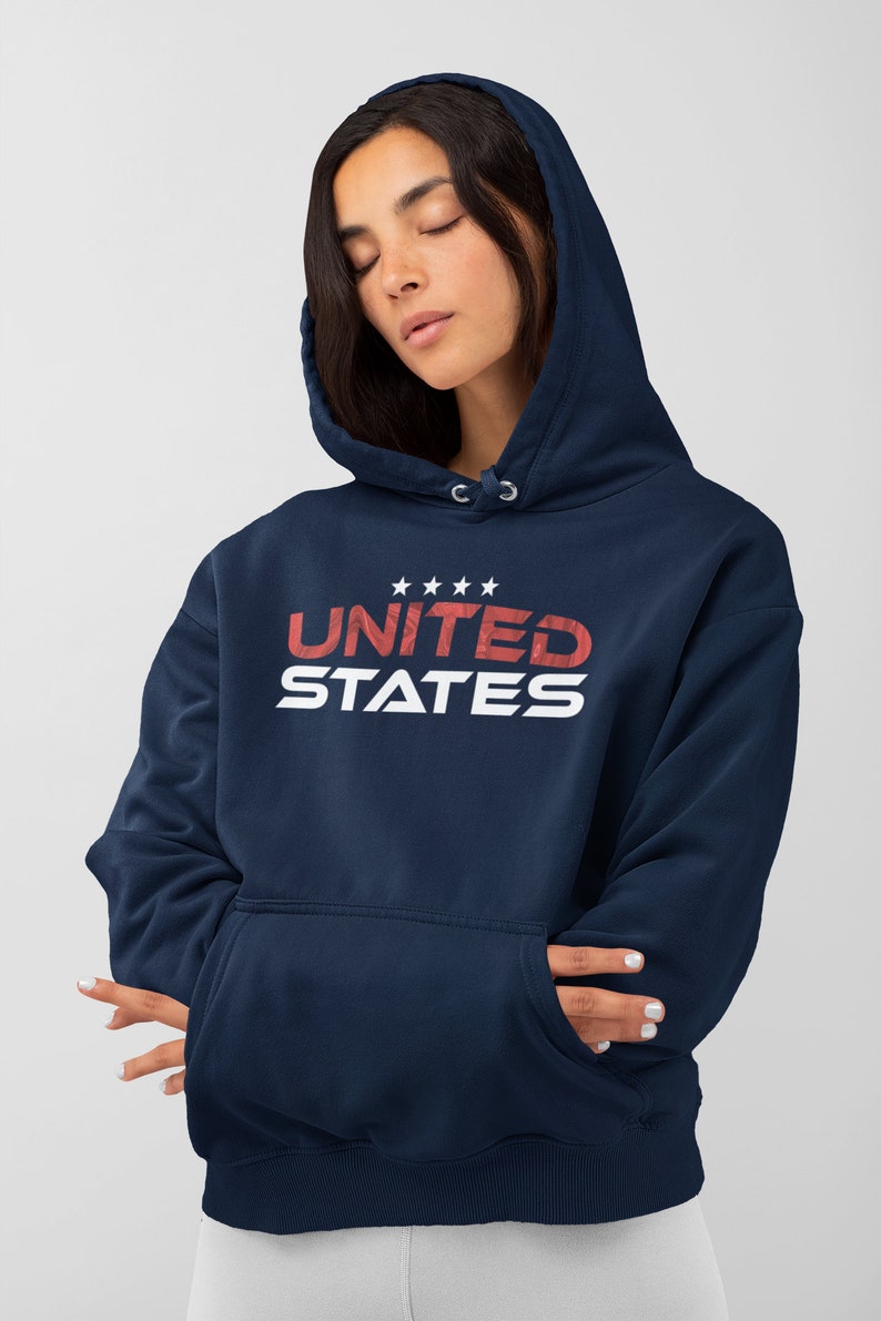 Op de afbeelding: Een marineblauwe hoodie met een witte en rode grafische print die "UNITED STATES" zegt met vijf sterren boven het woord "UNITED".