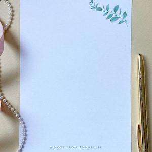 May include: A white stationery sheet with a green leafy branch design in the top right corner. The text "A note from Annabelle" is printed at the bottom of the sheet.