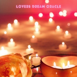 May include: A heart-shaped ceramic bowl with three lit candles inside, surrounded by a single orange rose and several small lit candles on a wooden surface. The text "LOVERS DREAM ORACLE" is displayed in pink neon letters above the bowl.