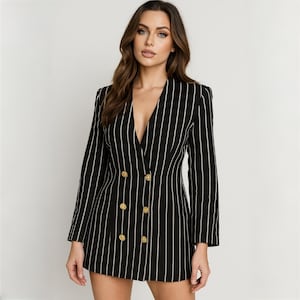 Puede incluir: Blazer a rayas blancas y negras con diseño de doble botonadura. El blazer presenta botones dorados y un escote en V. La chaqueta de manga larga tiene rayas verticales.