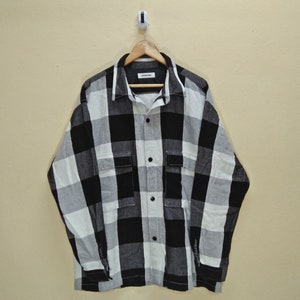 Peut inclure: Chemise en flanelle à carreaux noirs et blancs avec un devant boutonné et des manches longues.