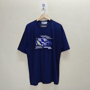 May include: Navy blue t-shirt featuring a graphic of a blue and yellow car with the text "SUBARU IMPREZA WRX STI VER V TYPE R". The shirt is hanging on a wooden hanger.