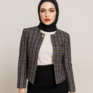 May include: A brown, blue, and black plaid jacket with a round collar and a single gold button. The jacket is worn over a white top and paired with a black skirt. The outfit is completed with a black head covering.