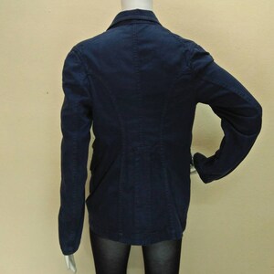 May include: A dark blue blazer with a long sleeve and a button closure. The blazer has a fitted silhouette and a back vent.
