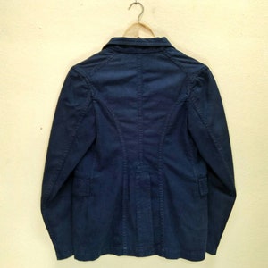 May include: A dark blue blazer with long sleeves and a button closure. The blazer has a classic style and is made of a smooth, textured fabric.