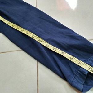 May include: A close-up of the navy blue sleeve of a shirt with a yellow measuring tape showing 29 inches.