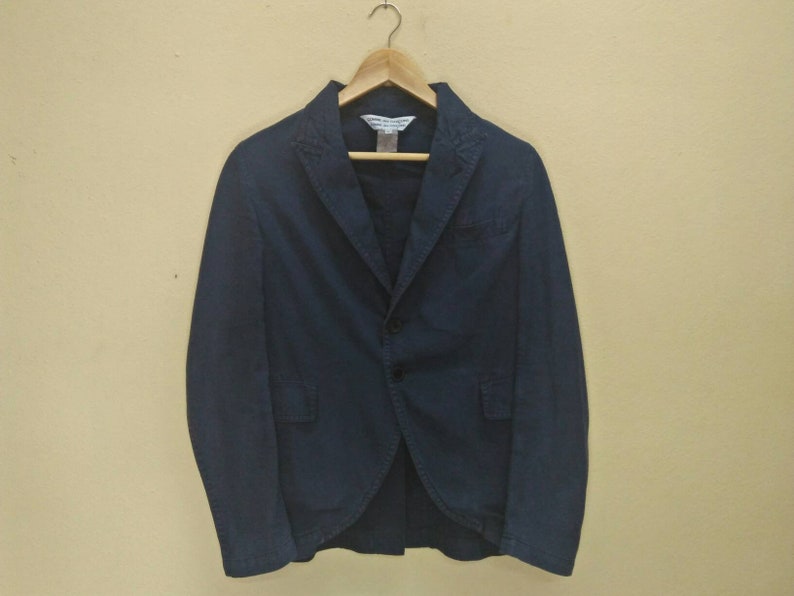 May include: A dark blue blazer with a single button closure and two pockets. The blazer has a classic style and is made of a soft, comfortable fabric.
