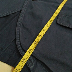 May include: A dark blue jacket with a yellow measuring tape. The tape measures 26 inches.