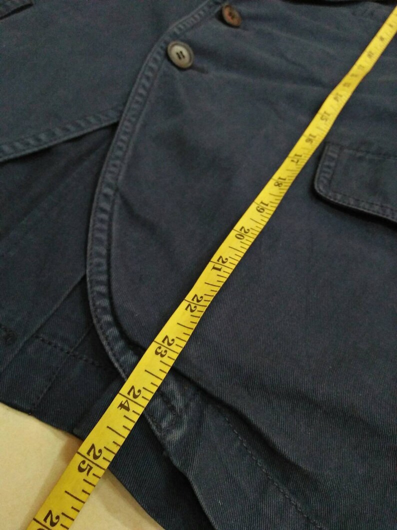 May include: A dark blue jacket with a yellow measuring tape. The tape measures 26 inches.
