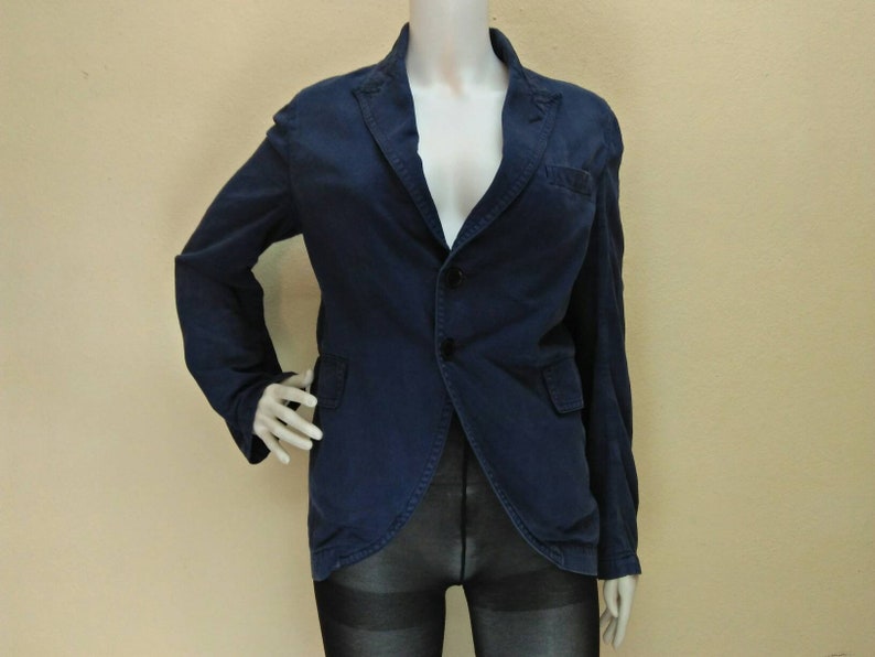May include: A dark blue blazer with a single button closure and two pockets. The blazer has a slightly fitted silhouette.