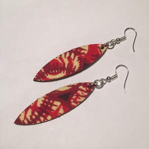 May include: A pair of red and cream colored fabric earrings with a leaf pattern. The earrings are oval shaped and have silver hooks.
