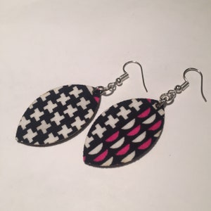 May include: A pair of black and white patterned earrings with silver hooks. One earring has a houndstooth pattern, and the other has a black and white pattern with pink accents.